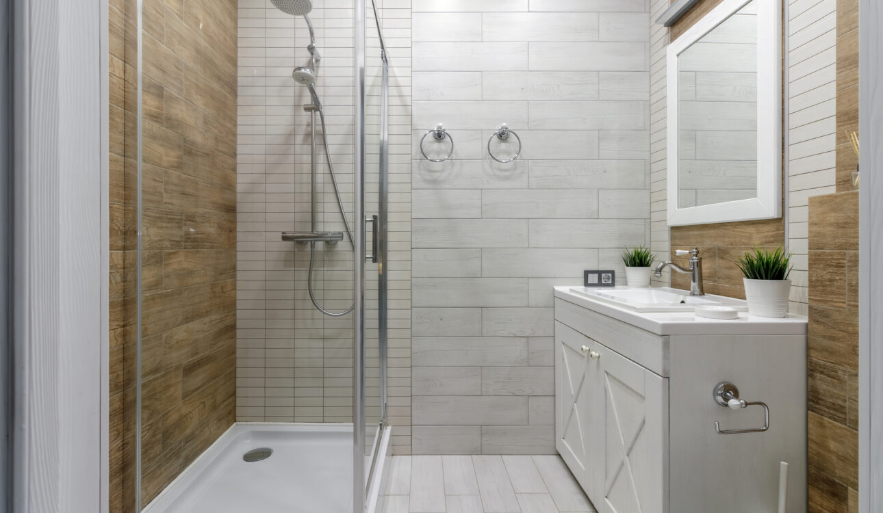 A clean and functional bathroom design featuring modern fixtures, wooden accents, and a glass-enclosed shower creating a warm and inviting atmosphere