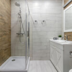 A clean and functional bathroom design featuring modern fixtures, wooden accents, and a glass-enclosed shower creating a warm and inviting atmosphere