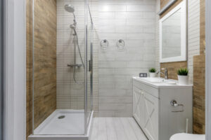 A clean and functional bathroom design featuring modern fixtures, wooden accents, and a glass-enclosed shower creating a warm and inviting atmosphere